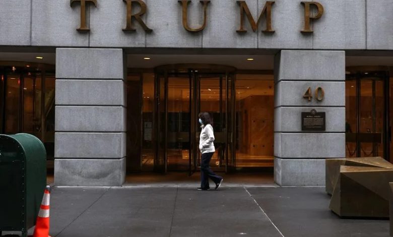 A woman wearing a protective face mask walks by 40 Wall Street, also known as the Trump Building, in New York City