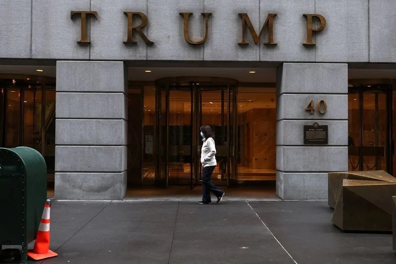 A woman wearing a protective face mask walks by 40 Wall Street, also known as the Trump Building, in New York City